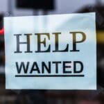 Alcorn County Unemployment at 2.9% in August, Below State Help Wanted sign in a store window, illustrating Alcorn County unemployment figures