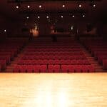 Corinth Theatre-Arts Eviction Stands After Appeal Fails Empty theater with rows of red seats facing a lit stage, illustrating the Corinth Theatre-Arts eviction