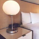 Corinth TownePlace Suites Ribbon Cutting Set for Sept. 29 Hotel room nightstand lamp beside a bed, illustrating the Corinth TownePlace Suites ribbon cutting