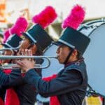 Crossroads Marching Classic Returns to Corinth Saturday Marching band trumpet players in plumed hats performing, similar to bands at the Crossroads Marching Classic