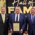 NEMCC Hall of Fame Honors Six Inductees at Homecoming Three men in suits holding a plaque in front of a NEMCC Hall of Fame backdrop at Northeast Mississippi Community College