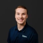 NEMCC graduate Jaxson Laster lands quality-engineer role after apprenticeship and international exchange Portrait of a smiling young man wearing a navy polo with a visible 'hago Automotive' logo