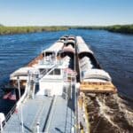 Yellow Creek Port Expansion Underway in Tishomingo County Cargo barge moving freight on a river, illustrating the Yellow Creek Port expansion