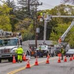 ACE Power Crew Heads to Alabama to Help After Isaias Utility line workers in bucket trucks repair overhead power lines on a residential street, illustrating an ACE Power crew on storm duty