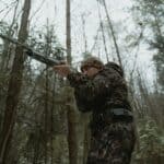 The 5 Best Insulated Coveralls for Alcorn County Deer Season Hunter in camouflage gear in a winter forest during deer season