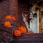 The 5 Best Outdoor Halloween Decorations for Alcorn County Yards Carved jack-o'-lanterns and spider-web decorations on a brick front porch