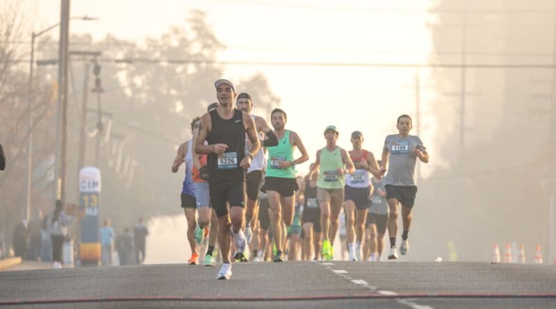 Runners with race bibs on a foggy morning street, illustrating the Cat Reman Challenge 5K going virtual