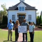 Corinth Beautiful Business of the Month: The Carriage House Four people hold a Beautiful Business of the Month sign in front of The Carriage House in Corinth