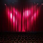 Corinth Dramatic Society Gets Playhouse Lease From City Empty theater stage with red curtains, illustrating the Corinth Dramatic Society playhouse lease