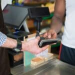 Corinth Sales Tax Ends Fiscal Year Up 7.5 Percent Shopper paying with a card at a store checkout, illustrating Corinth sales tax growth