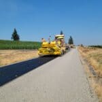 Farmington Road Paving Contract Approved in Alcorn County Paving crew laying fresh asphalt on a rural two-lane road, illustrating Farmington Road paving in Alcorn County