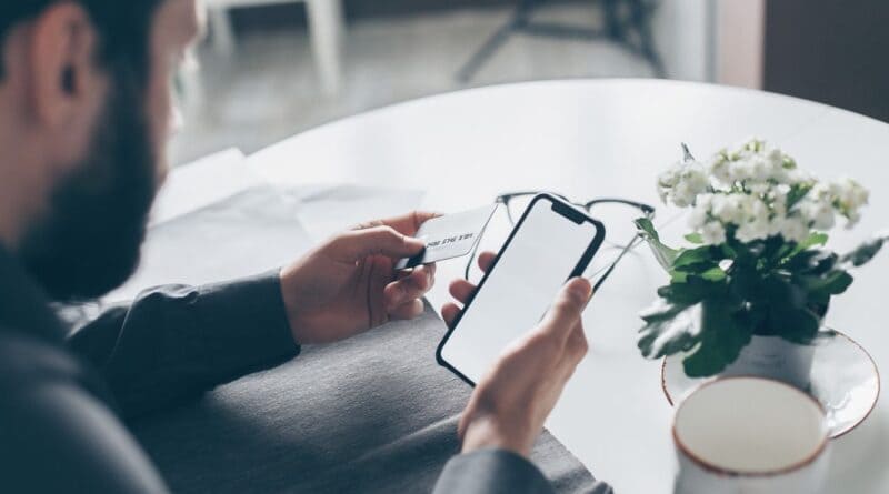 Person holding a credit card and smartphone, illustrating a utility bill scam payment demand