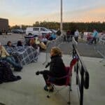 Crowd Gathers Before Sunrise for Trump Rally at Corinth's Crossroads Arena Supporters in lawn chairs wrapped in blankets wait behind barricades outside the Crossroads Arena in Corinth before sunrise ahead of the Trump rally